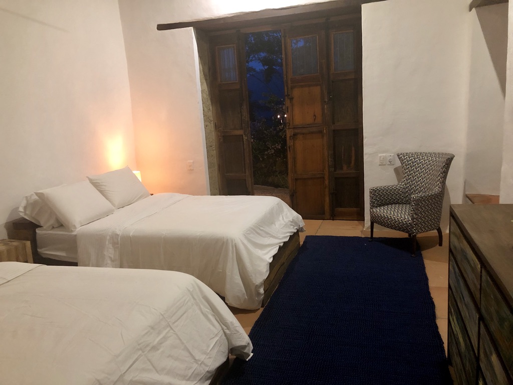 Twin double beds lit softly at night beside the timber doors