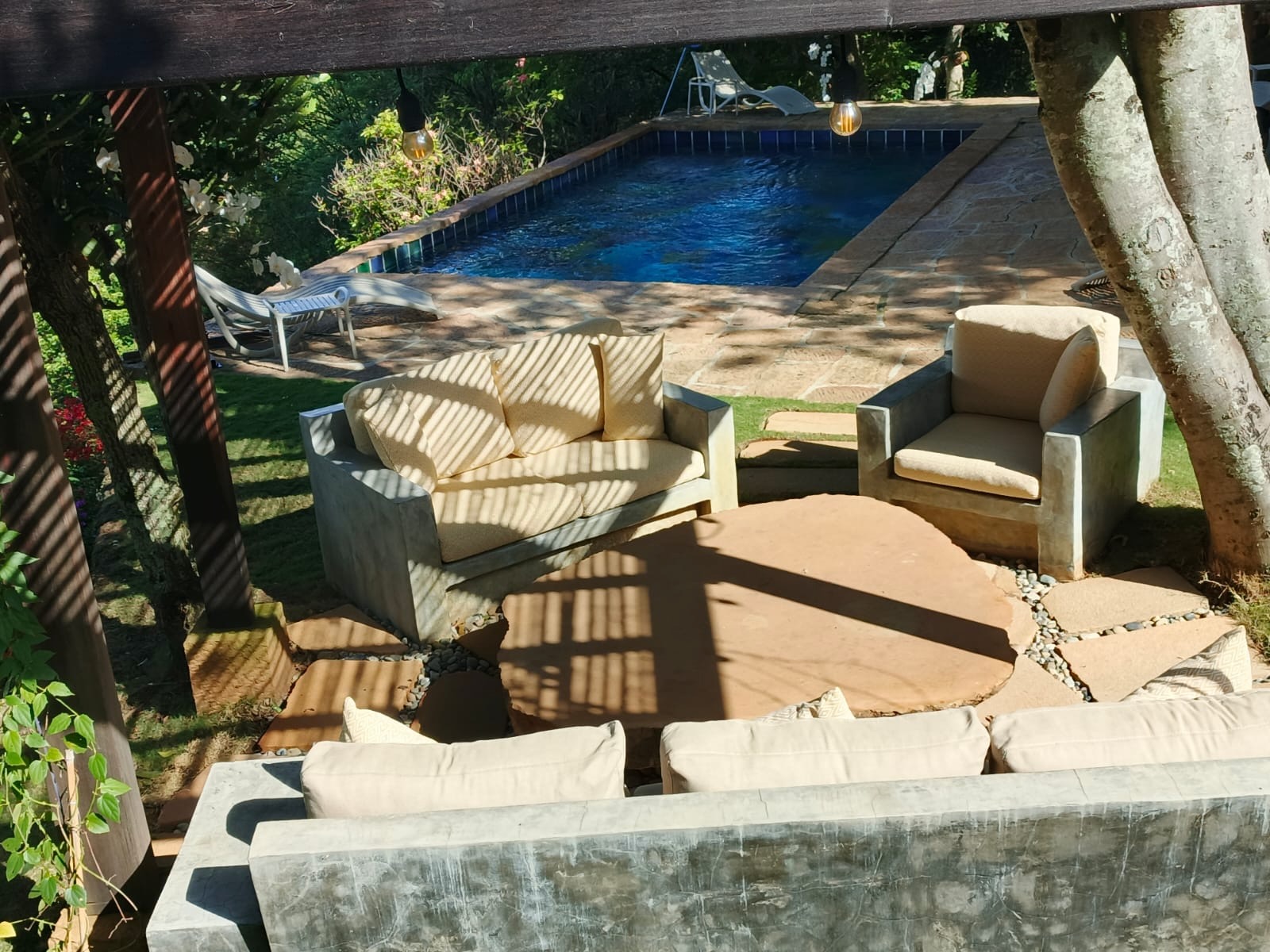 Blue-tiled pool seen from the shaded garden lounge