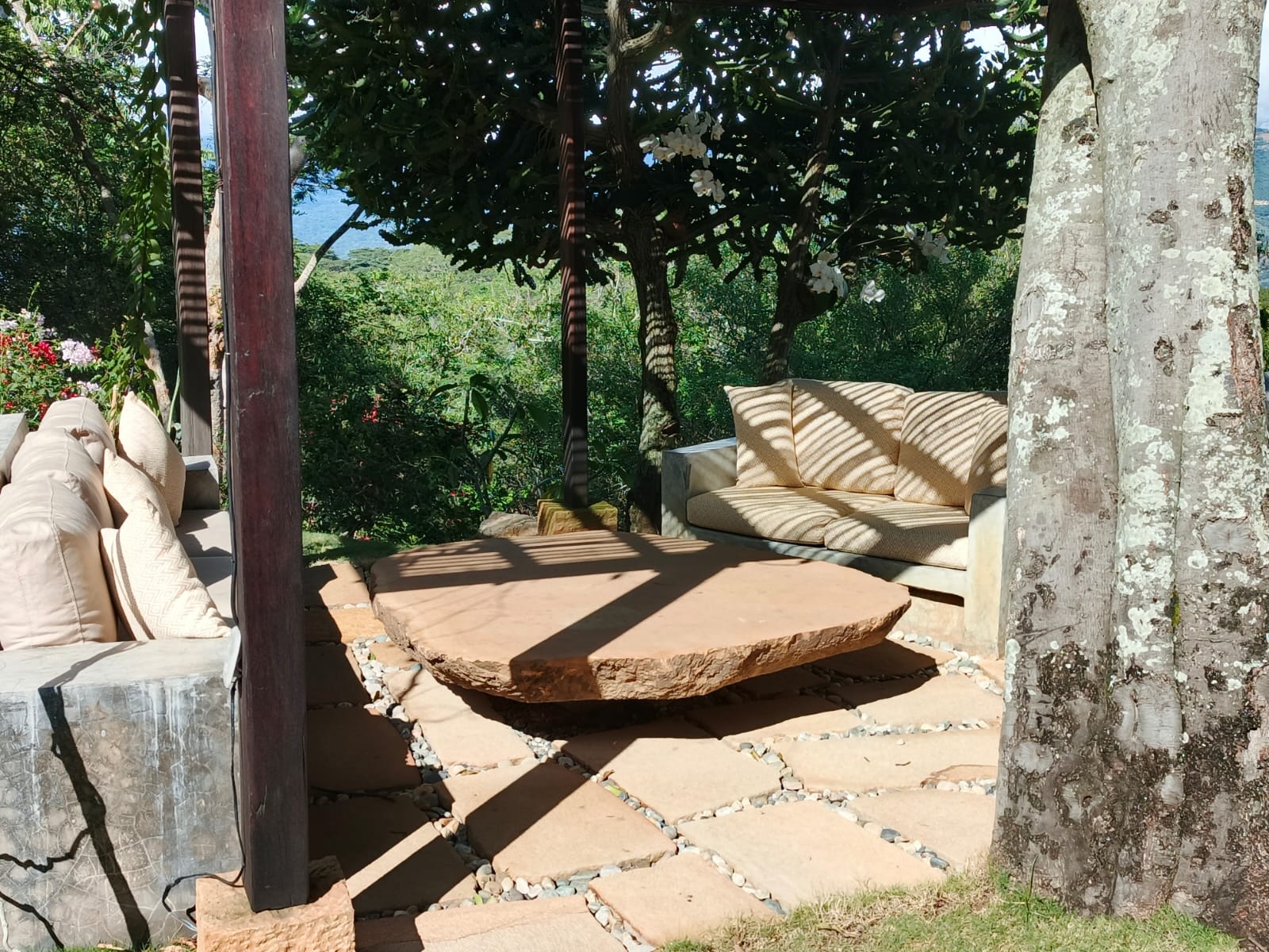 Carved stone table and sofas beneath the frangipani tree