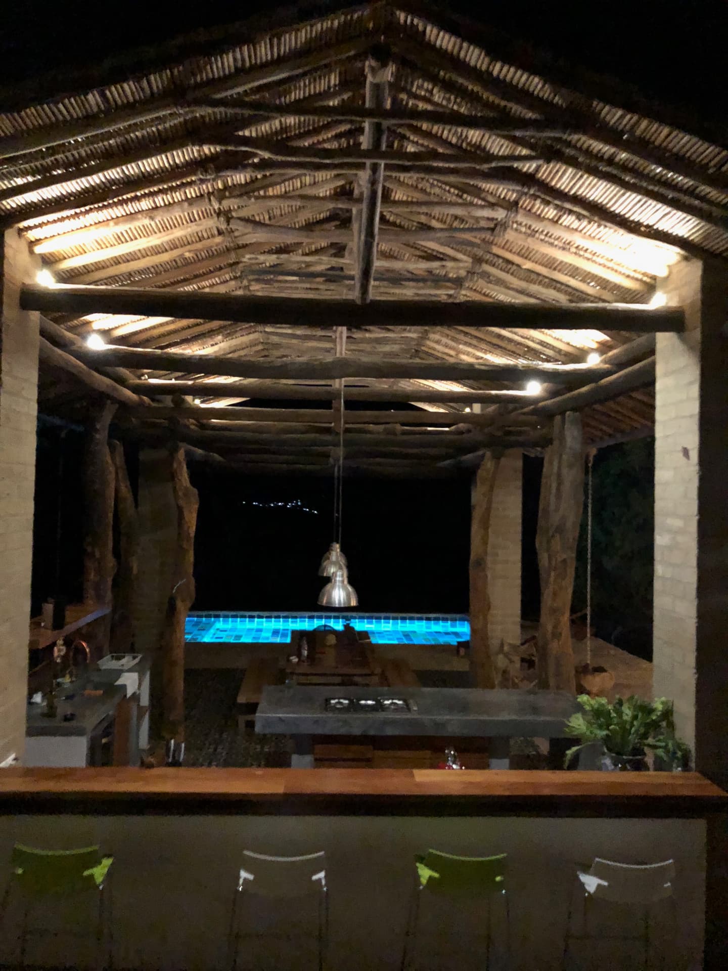 The open kitchen and bar lit at night above the pool