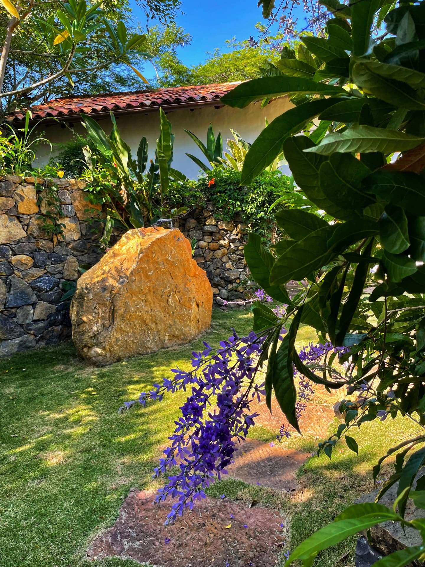 Sandstone boulder and purple flowers in the garden