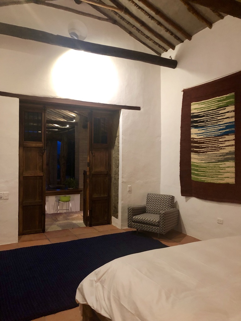 Bedroom at night with a woven wall hanging beneath hand-hewn roof beams