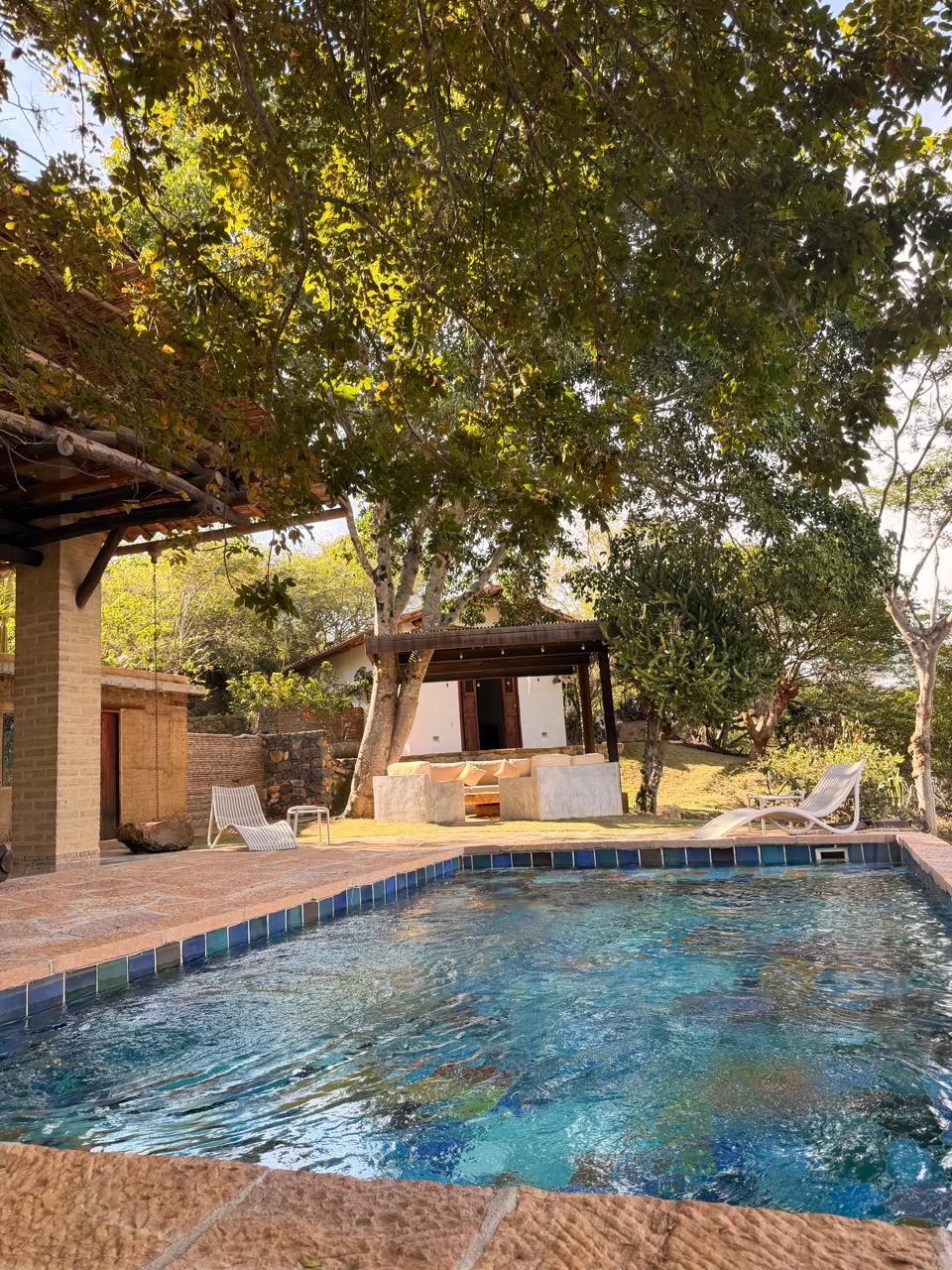Shaded pool terrace with mosaic-tiled water, garden lounge and mountain views