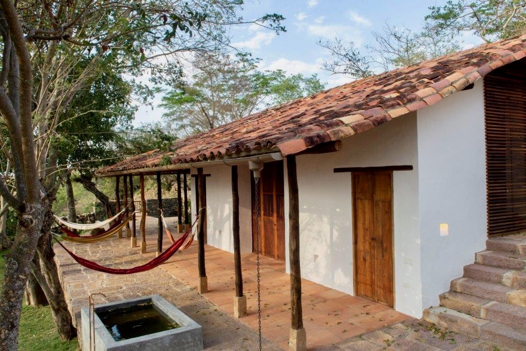 Hammocks under the clay-tile veranda beside the stone water basin