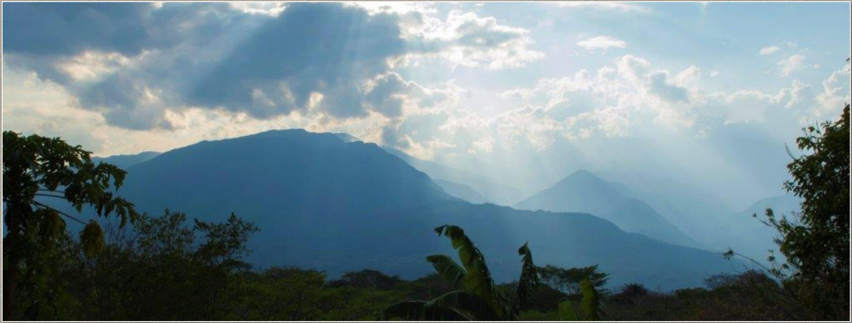 The Uchata mountain range across the Suárez river with sun breaking through the clouds