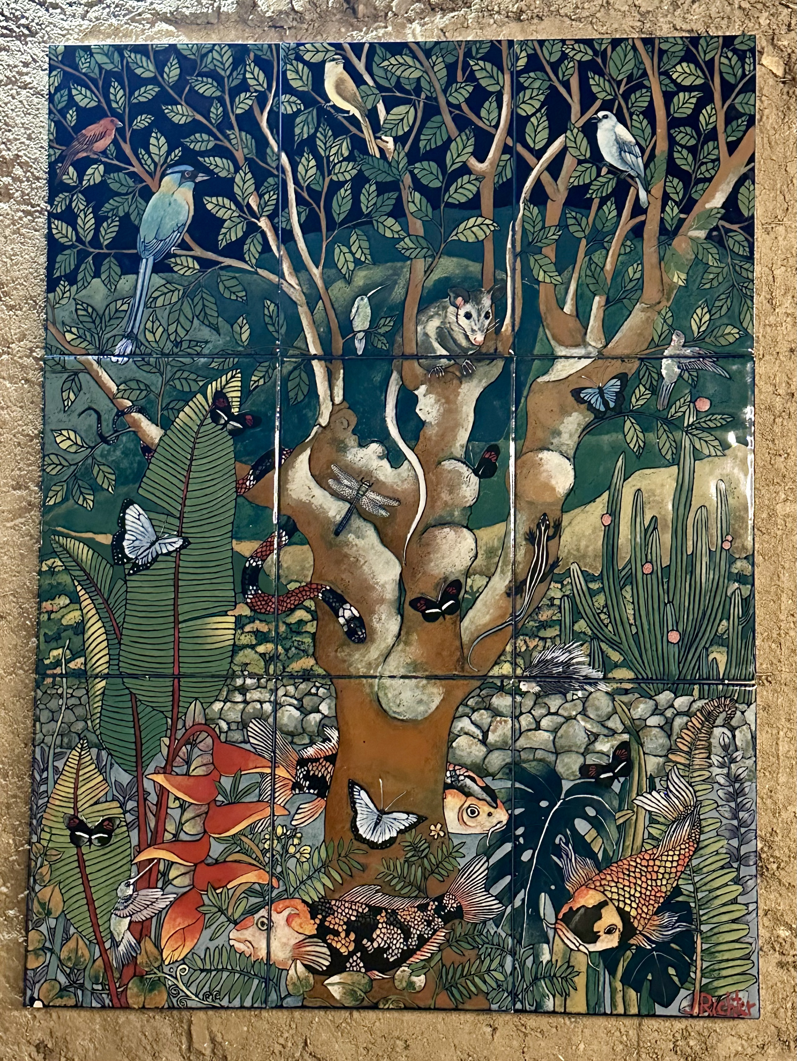 Decorative tile with a bird among leaves set into a whitewashed stone wall