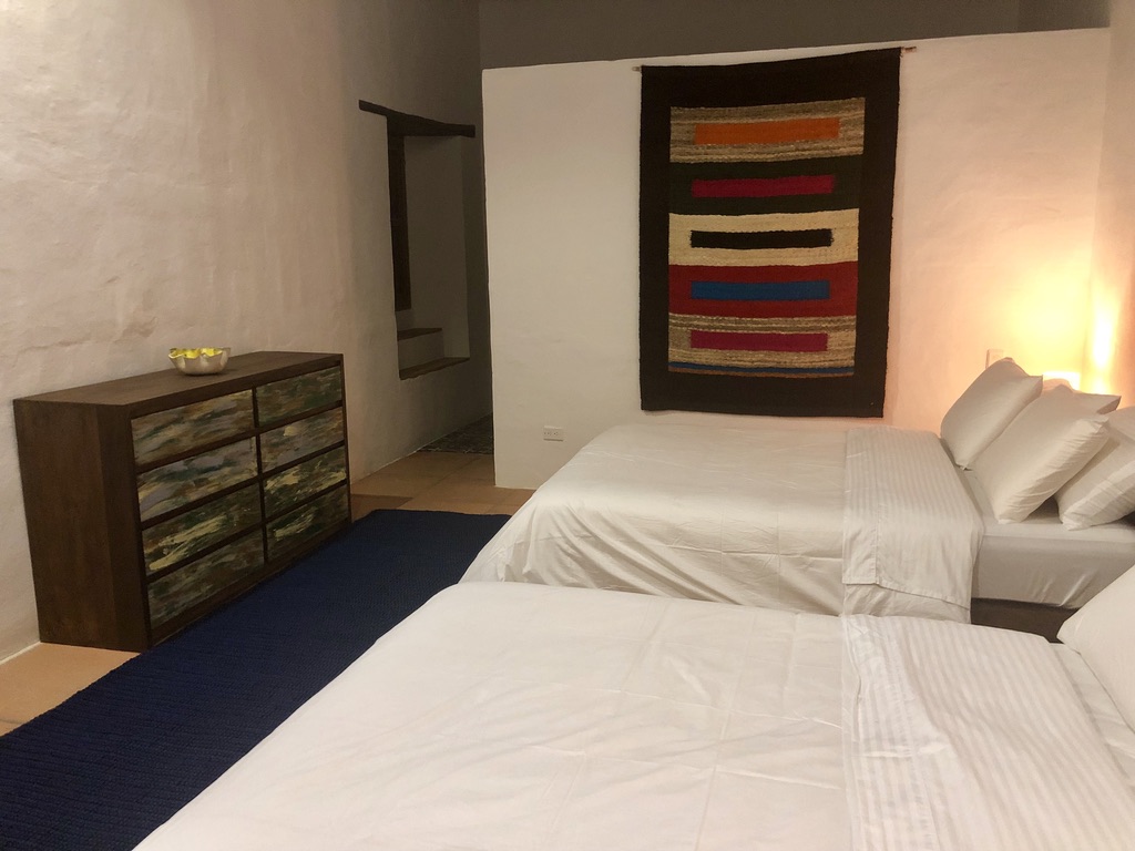 Twin double beds with a striped Colombian tapestry and painted dresser