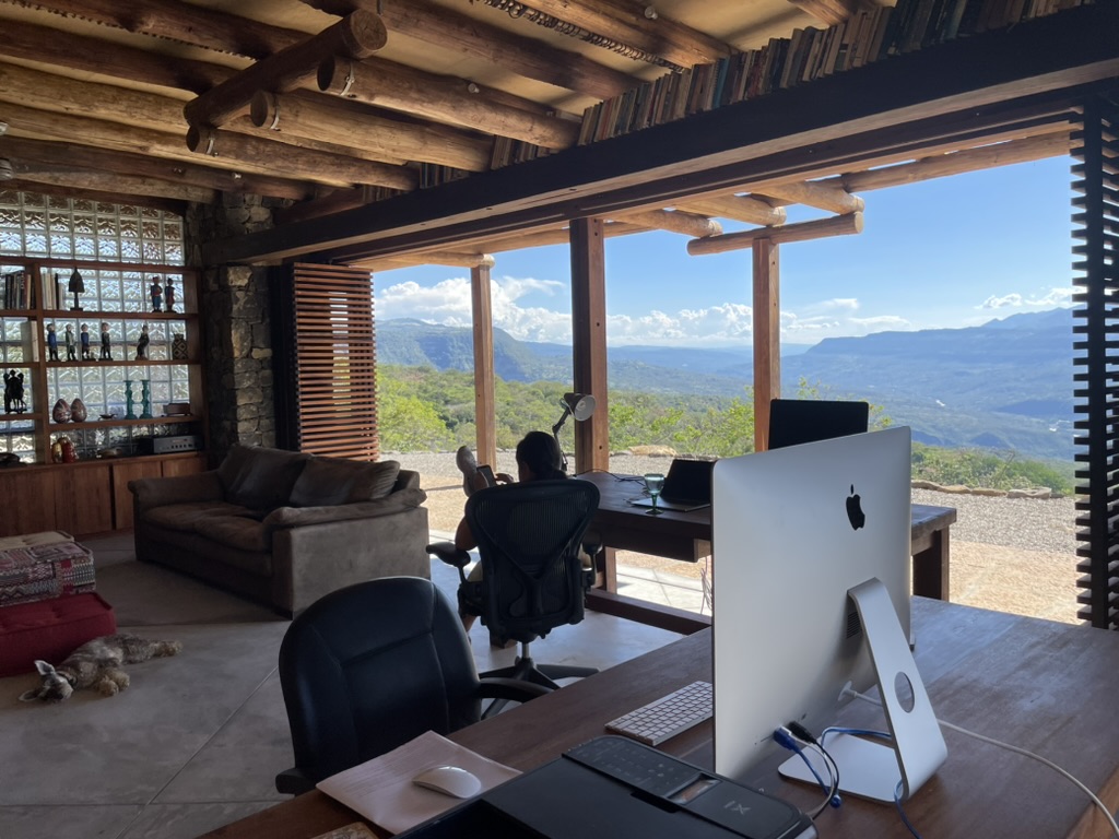 Workspace and lounge sharing one open room beneath hand-hewn log beams