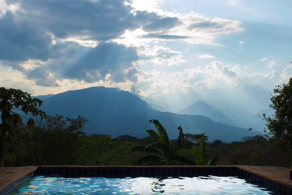 Infinity-edge pool looking across the Uchata mountains as light breaks through the clouds