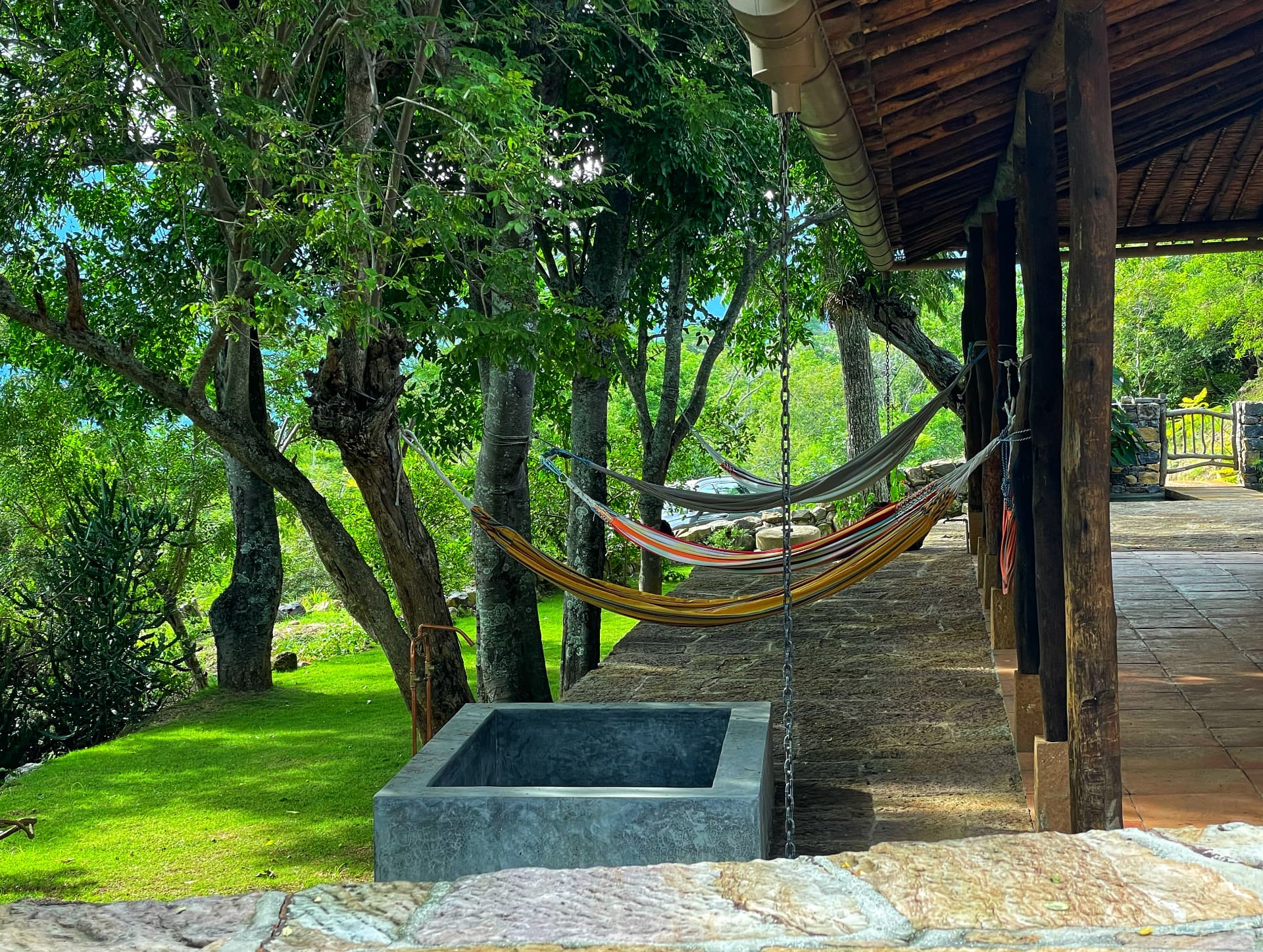 Hammocks under the timber veranda beside the stone plunge basin and lawn