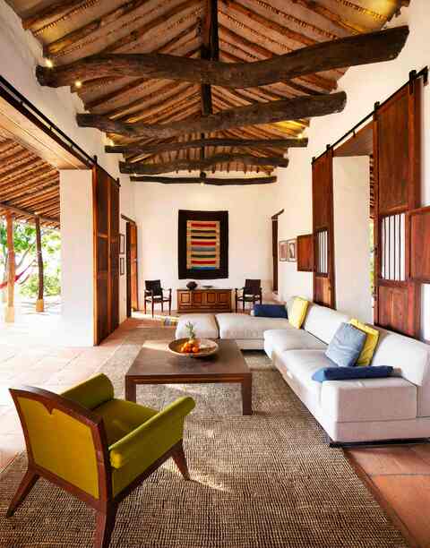 Open living room with exposed timber beams, sliding wooden doors and linen sofas on a jute rug