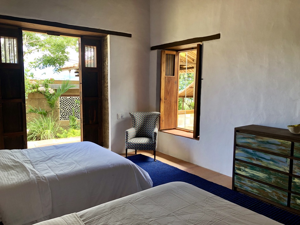 Twin double beds beside an open window over the garden and swing