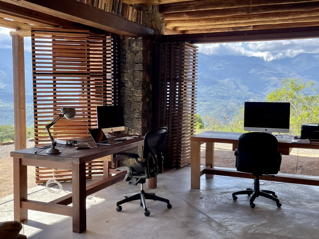Two timber desks with ergonomic chairs open to the mountains behind slatted wooden screens